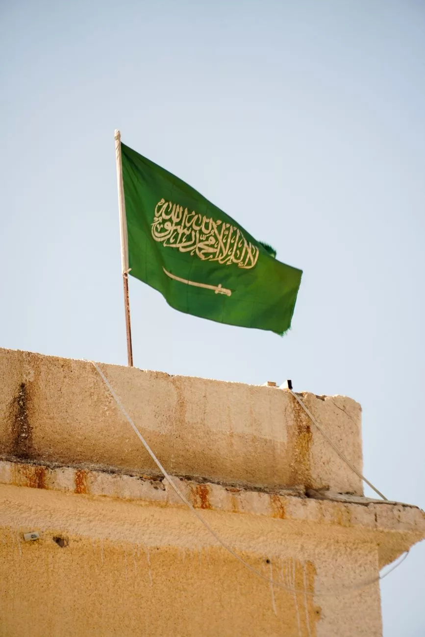 Flaga Arabii Saudyjskiej powiewająca na dachu budynku w Medynie, w Arabii Saudyjskiej, pod czystym niebem.