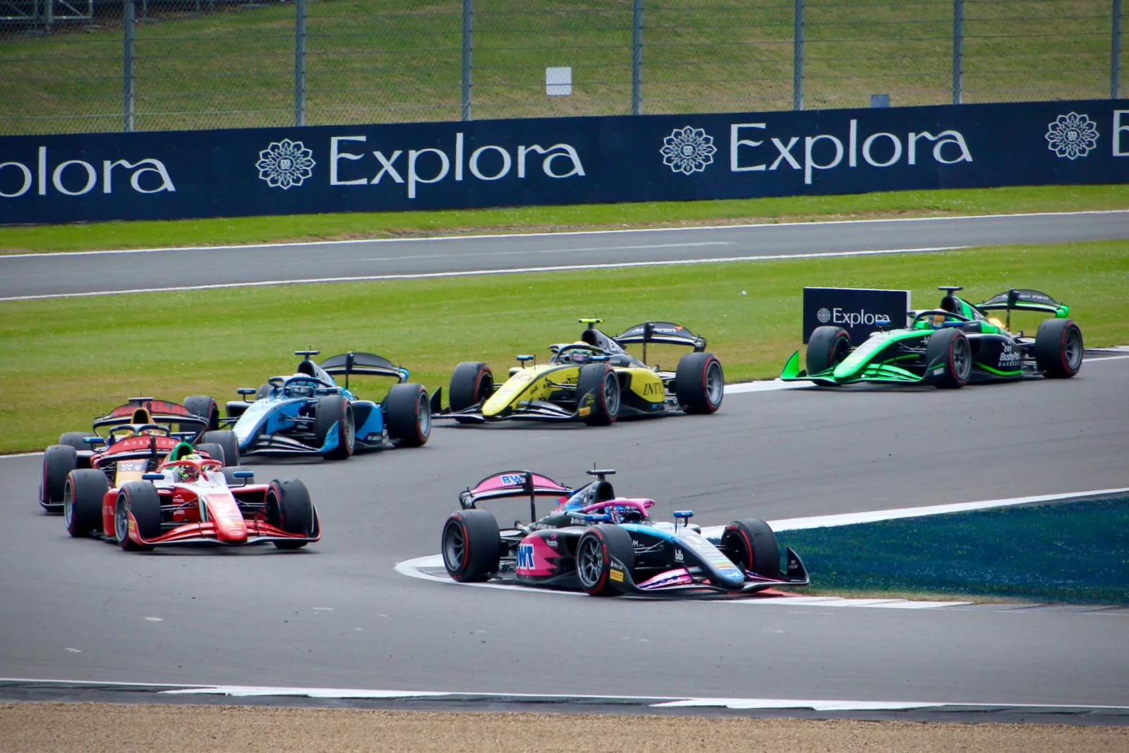 Emocjonujący wyścig Formuły 1 na torze Silverstone, w którym kolorowe samochody rywalizują o prowadzenie na torze.